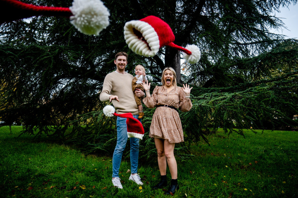 a family throwing Christmas Santa hats at the photographer