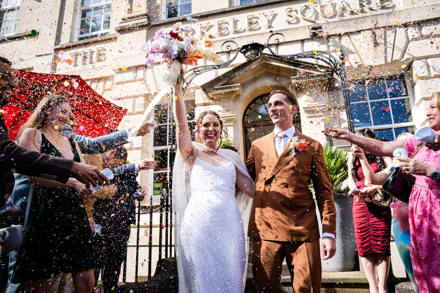 Bride and groom walking through confetti outside The Square Club, Bristol after their ceremony
