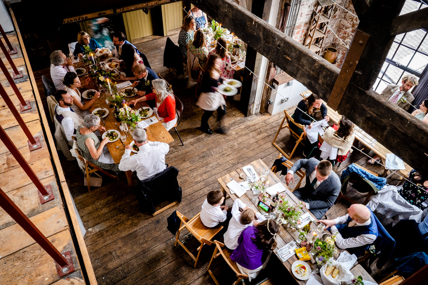 Overhead view of wedding guests dining at long tables inside The Forge Bristol industrial wedding venue