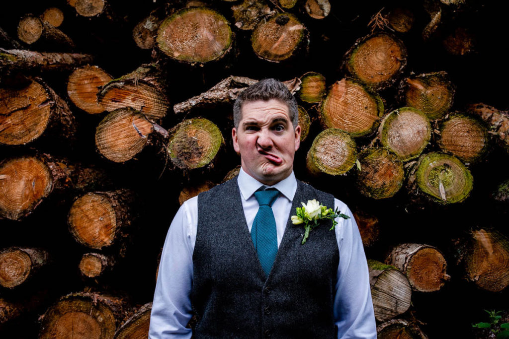 Funny face wedding photo infront of the logs at high barn