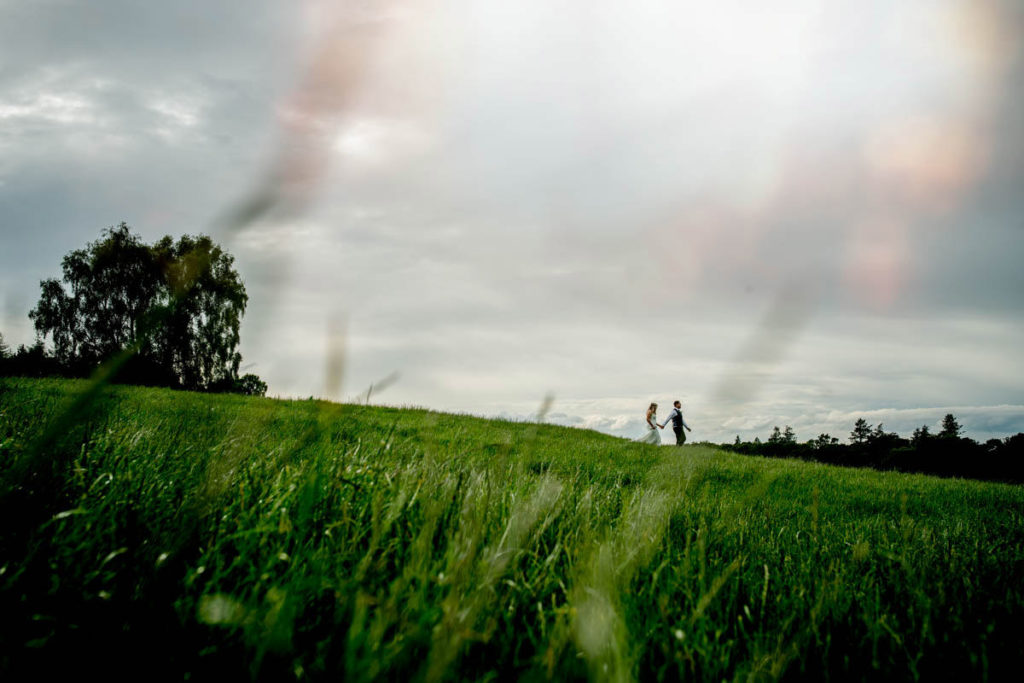 Wedding photography portrait of couple walking across the field at a high barn wedding in edenhall