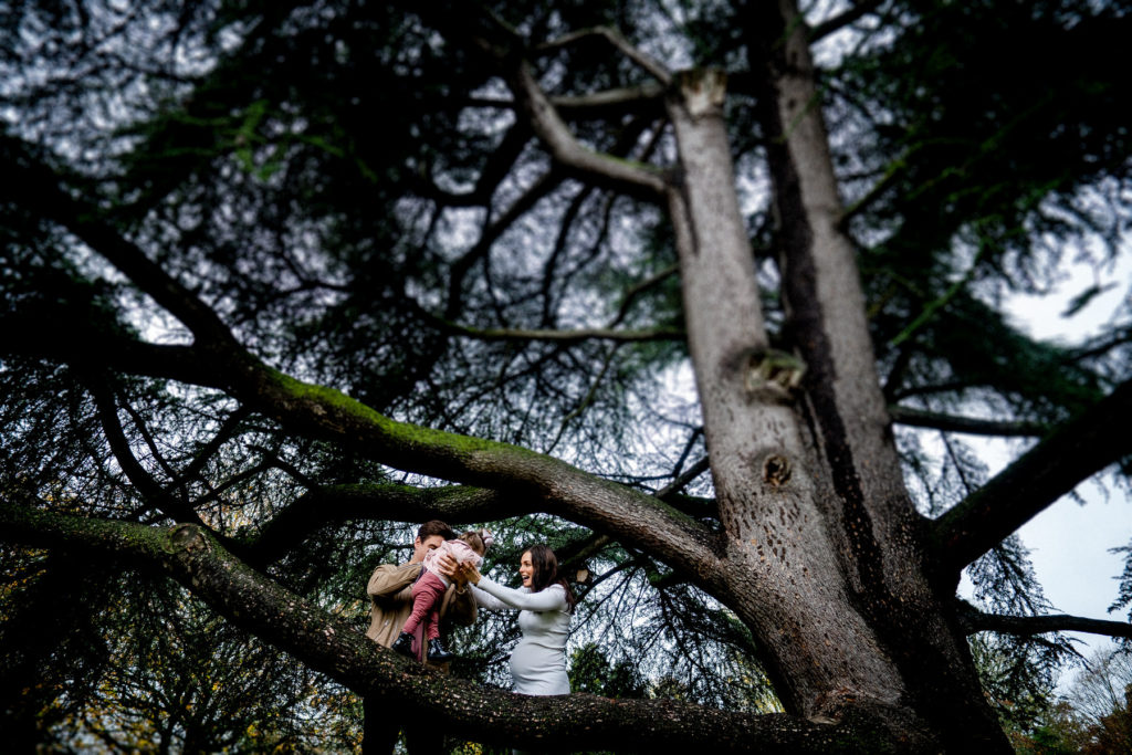 a young girl climbing on a tree as mum and dad support her