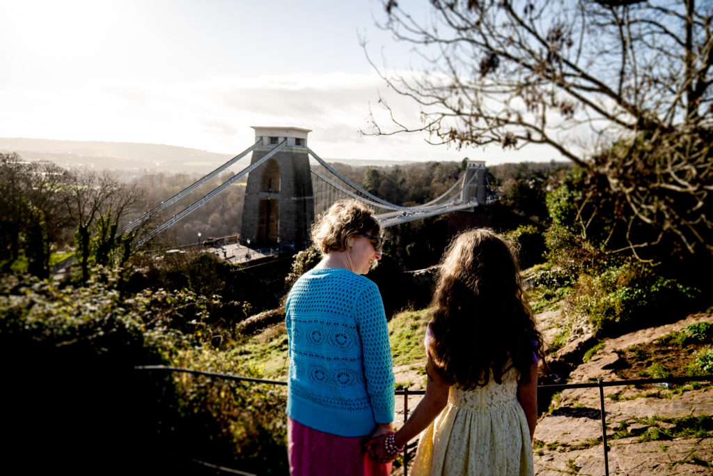 A mum and daughter holding hands overlooking the Clifton suspension bridge