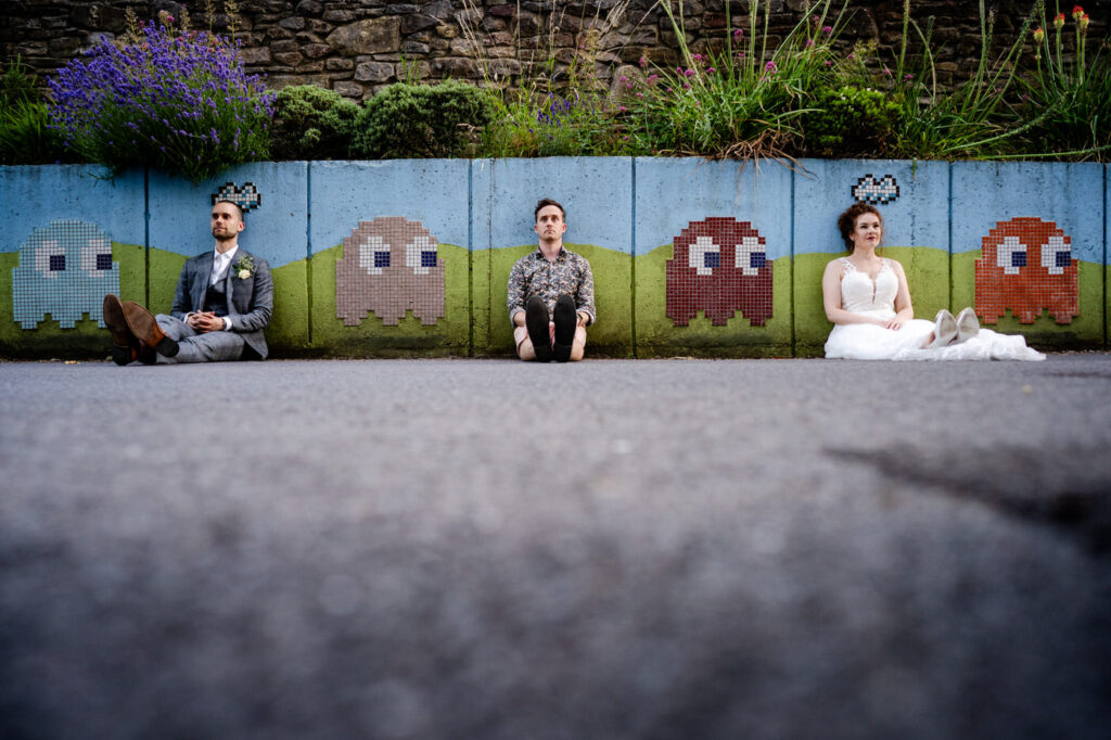photographer joins the wedding couple in a selfie portrait on a Mari kart wall