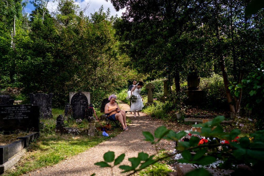wedding couple walk past a women mourning by a grave